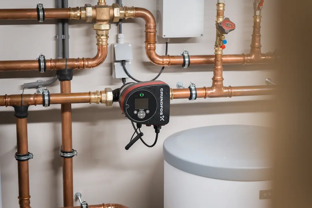 Detail van verwarmingssysteem met circulatiepomp en koperleidingen in technische ruimte
